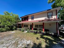 Charming two-story home featuring a screened porch, red accents, and mature landscaping at 14633 Sassandra Dr, Odessa, FL 33556