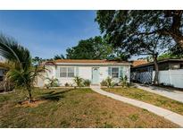 Quaint white one-story home with mature trees, tidy landscaping, and a welcoming walkway to the front entrance at 2261 Queen S St, St Petersburg, FL 33712