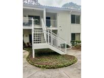 Exterior of a condominium featuring white walls, balcony, stairs, and well-maintained landscaping at 3629 Indigo Pond Dr # 3629, Palm Harbor, FL 34685