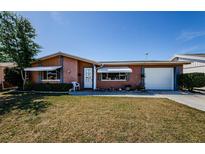Charming single-story home with a well-maintained lawn, awnings, and attached garage at 4210 Newbury Dr, New Port Richey, FL 34652