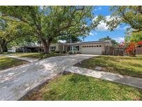 Charming single-story home with a well-manicured lawn, mature trees, and a two-car garage at 9044 Lynwood Dr, Seminole, FL 33772