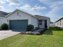 Charming single-Gathering home featuring a beautifully landscaped front yard and a teal two-car garage at 11833 Clare Hill Ave, Riverview, FL 33579