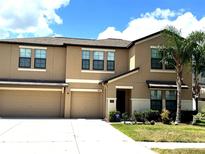 Two-story townhome with a beige exterior, well-maintained landscaping, and an attached two-car garage at 14050 Arbor Pines Dr, Riverview, FL 33579
