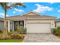 Charming single-Gathering home featuring a two-car garage, beautiful landscaping, and a classic tile roof at 17800 Solstice Ave, Venice, FL 34293