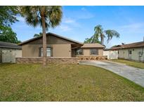 Charming single-story home with stucco exterior, stone accents, driveway, lawn and mature landscaping at 611 Limetree Dr, Oldsmar, FL 34677
