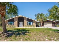 Charming single-story brick home featuring an expansive lawn and a detached two-car garage at 7169 Spruce Dr, Weeki Wachee, FL 34607