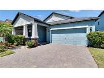 Charming home with blue siding, manicured landscaping and paver driveway leading to a two-car garage at 7215 Wash Island Dr, Sun City Center, FL 33573