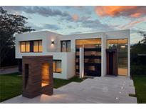 Modern home showcasing unique architecture, with geometric shapes, large windows, and minimalist design under a cloudy sunset sky at 77 Avonwood, Tampa, FL 33625