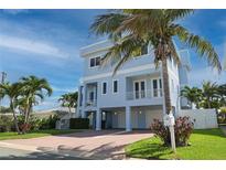 Inviting light blue three-story home with a brick driveway and lush tropical landscaping at 11105 5Th E St, Treasure Island, FL 33706