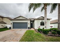 Charming single Gathering home with a well-manicured lawn, palm trees, and a brick paved driveway at 1155 Lawnview Ter, New Port Richey, FL 34655