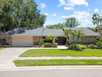 Charming single-story home features a manicured lawn and lush landscaping at 1810 Pine Hill Dr, Safety Harbor, FL 34695