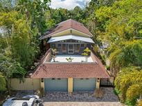 Unique home design featuring a two-car garage, rooftop patio, and screened outdoor living space at 515 Orange St, Palm Harbor, FL 34683