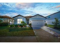 Charming single-story home with a well-manicured lawn illuminated at dusk at 6426 Bradford Woods Dr, Zephyrhills, FL 33542