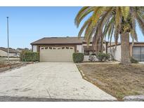 Charming home featuring a large garage, well-maintained landscaping, and a beautiful palm tree at 7509 Rocky Point Dr, Hudson, FL 34667