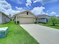 Charming single-story home with a well-manicured lawn and a two-car garage on a sunny day at 7737 Sail Clover Ln, Zephyrhills, FL 33540