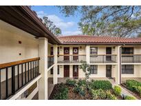 Condo exterior with red tile roof, upper and lower door wreaths, black railings, and mature landscaping at 110 Hammock Pine Blvd # 110, Clearwater, FL 33761