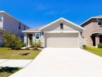 Charming one-story home with a manicured lawn and a two-car garage under a bright blue sky at 16805 Delia St, Wimauma, FL 33598