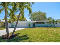 Charming single-story home showcasing a manicured lawn, tropical landscaping, and a two-car garage at 4036 Church Creek Pt, Largo, FL 33774