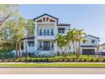 Two-story home boasting white siding, balcony, dark trim, manicured lawn, and complemented by lush palm trees at 526 39Th S Ave, St Petersburg, FL 33705