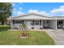 Charming single-story home featuring a well-manicured lawn, gray brick facade, and a convenient carport at 10008 Daffodil N St # 186, Pinellas Park, FL 33782