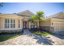 Charming home featuring a red front door, stone accents, lush landscaping, and a paver driveway at 14809 Tudor Chase Dr, Tampa, FL 33626