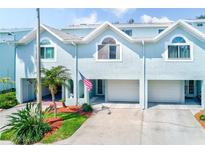Charming light blue townhouse with a one-car garage, nice landscaping and a visible American flag at 615 Garland Cir, Indian Rocks Beach, FL 33785