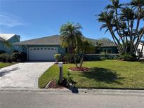 Charming home with a well-manicured lawn, palm trees, and a brick driveway at 6319 Cocoa Ln, Apollo Beach, FL 33572