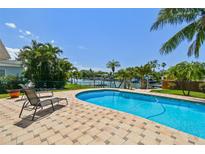 Outdoor pool surrounded by a paver patio, lush landscaping, and scenic water views at 6667 28Th S St, St Petersburg, FL 33712