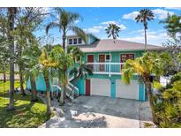 Inviting two-story turquoise home with palm trees, white trim, red doors, and a two-car garage at 7500 141St St, Seminole, FL 33776
