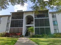 Exterior view of a multi-story condo building with screened-in balconies and lush landscaping at 1309 Pine Ridge E Cir # H3, Tarpon Springs, FL 34688