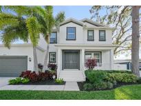 Stunning two-story home featuring a welcoming front porch, gray double-door entry, and beautiful tropical landscaping at 2904 W Averill Ave, Tampa, FL 33611