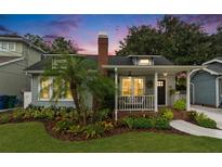 Charming home featuring mature landscaping, a brick chimney, and an inviting front porch at 2910 W Aquilla St, Tampa, FL 33629