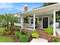 Charming home featuring a brick front porch and beautifully landscaped yard with vibrant plants and a welcoming entrance at 2910 W Aquilla St, Tampa, FL 33629
