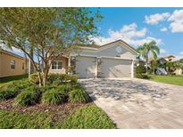 Charming single-story home featuring a paver driveway, manicured landscaping, and a two-car garage at 30174 Southernwood Ct, Wesley Chapel, FL 33543