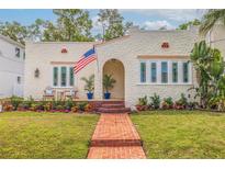 Charming stucco home with a beautiful brick walkway, arched entryway, and an American flag waving proudly at 3512 W Santiago St, Tampa, FL 33629