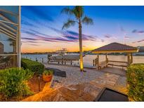 Beautiful waterfront view featuring a private dock, boat lift, and charming gazebo perfect for relaxation and enjoying the sunset at 5812 Mariners Watch Dr, Tampa, FL 33615