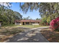 Charming single-story home with red brick and a driveway surrounded by lush greenery and trees at 9825 Casey Dr, New Port Richey, FL 34654
