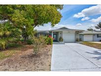 Charming single-story home with a well-maintained lawn and a freshly painted driveway at 1496 Queen Anne Dr, Palm Harbor, FL 34684