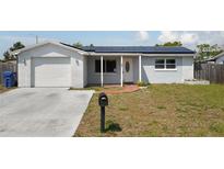 Charming single-story home featuring a brick and stucco facade, solar panels, and a well-manicured lawn at 3207 Coldwell Dr, Holiday, FL 34691