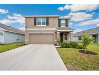 Two-story home with neutral paint, a two-car garage and black shutters at 36727 Spanish Rose Dr, Dade City, FL 33525