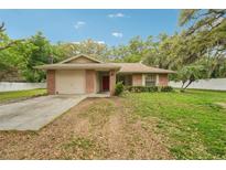 Charming brick home with a well-maintained lawn, a red door, and an attached garage at 6231 Massey Rd, Zephyrhills, FL 33542