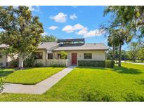 Charming single-story home featuring a well-manicured lawn, a red door, and a light gray exterior at 10 James Ct, Oldsmar, FL 34677