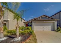 Charming home featuring a two-car garage, well-maintained landscaping, and a red front door at 10222 Cool Waterlily Ave, Riverview, FL 33578