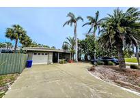 Charming single-story home with a two-car garage, lush landscaping, and a long driveway at 103 1St St, Belleair Beach, FL 33786