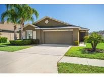 Charming one-story home with a two-car garage, green lawn, and palm tree landscaping at 12618 Sandpine Reserve Pl, Gibsonton, FL 33534