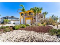 Charming yellow two-story home with lush landscaping, palm trees, and a two-car garage at 13514 Garris Dr, Hudson, FL 34667