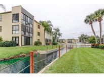 Beautiful condo complex featuring a canal, lush landscaping, and palm trees at 14130 Rosemary Ln # 3312, Largo, FL 33774