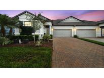 Charming townhome featuring a brick driveway, manicured lawn, and two-car garage at 16822 Balance Cv, Land O Lakes, FL 34638