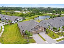 Stunning aerial view of a home featuring lush landscaping, private driveways, and a tranquil lake in the background at 19370 Hawk Valley Dr, Tampa, FL 33647