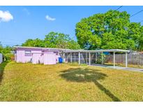 Backyard featuring a covered parking area, screened lanai, and lush landscaping at 2827 1St Ne St, St Petersburg, FL 33704